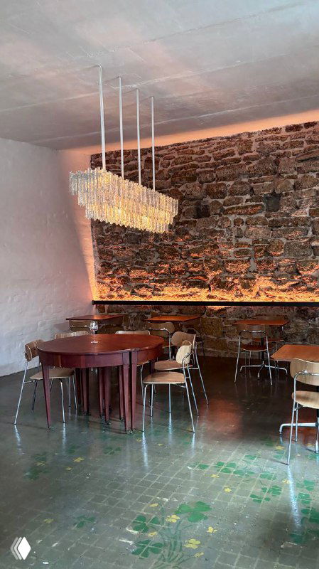 Общий вид зала с деревянными потолочными балками, круглым столом и стульями, приглушённая подсветка и свободное пространство в зале.