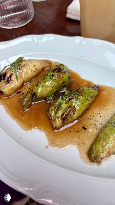 Тарелка с фаршированными патисонами в подливе — деталь меню ресторана, крупный план блюда с соусом и прожаркой.