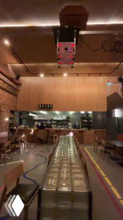 Внутренний вид бара «Кирпичик» в Ростове: длинный стол из стеклоблоков в центре зала, индустриальная отделка потолка и тёплое освещение.