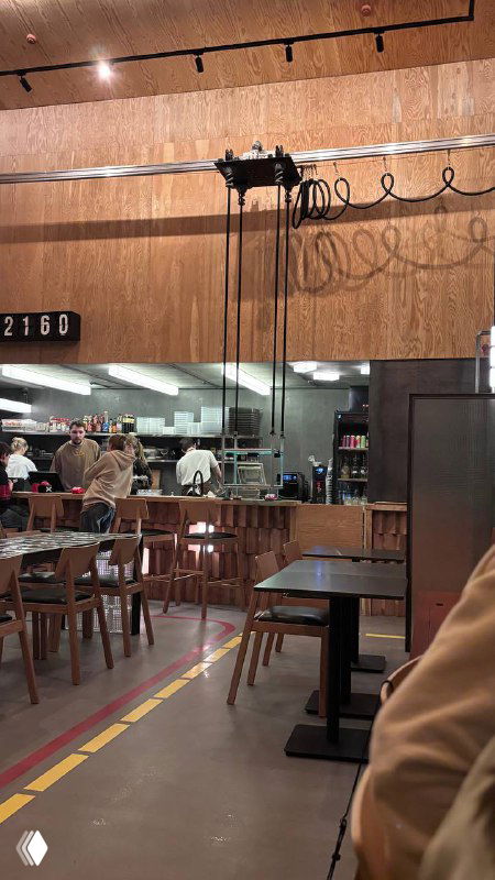 Вид на барную зону и открытую кухню в «Кирпичике»: рельсовый механизм и провода над зоной обслуживания, бытовой индустриальный стиль.