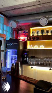 Ещё один угол бара с яркой цветовой подсветкой, холодильником и декоративными предметами — интерьерное фото в ретро‑вайбе Ростова.