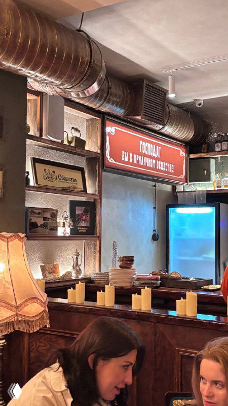 Интерьер с деревянными элементами, настольными лампами и декоративными буквами на полках — уютный ретро‑декор и детали бара.