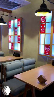 Уютные диваны и деревянные столы у окна, цветные витражи с масками и подвесные лампы в стиле идзакая.