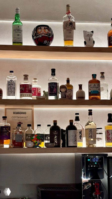 Подсвеченные полки с разнообразными алкогольными бутылками: сочетание японских и международных напитков в баре.