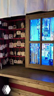 Небольшая алтарная зона или уголок с деревянными табличками-эмами и окном, через которое видно уличный неон.