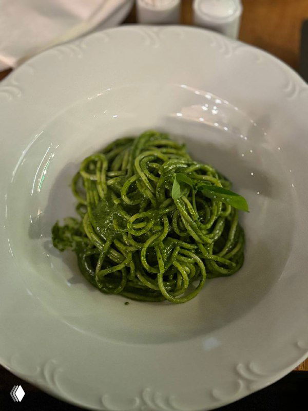 Тарелка спагетти, покрытая насыщенно-зелёным соусом песто, поданная в глубокой белой тарелке — подача в ресторане «Пробке».