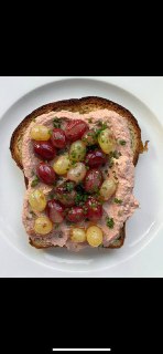 Крупный план: тост с паштетом из куриной печени и жареными виноградными ягодами на белой тарелке, видно текстуру и соусы