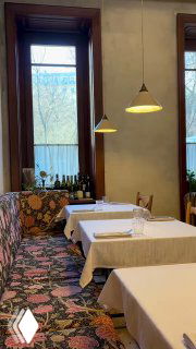 Интерьер ресторана Mamie: светлая зона с обеденными столами, настенные окна, лампы над столами и уютная атмосферная расстановка мебели.