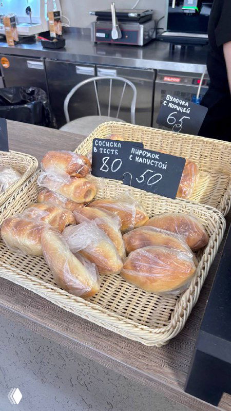 Пирожочки и выпечка на прилавке универской столовой: корзины с булочками и ценники, столовая атмосфера и ностальгический штрих посещения кампуса.
