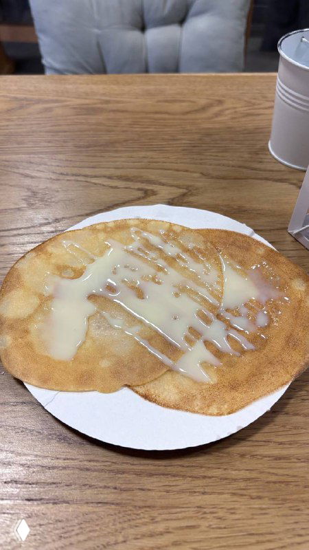 Тонкий блин с глазурью на белой тарелке, крупный план одной порции из маленького блинного заведения — аппетитный вид блюда.