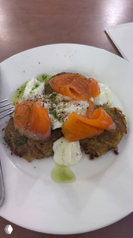 Блюдо из драников с лососем и страчателлой на белой тарелке, крупный план еды в трапезной при храме.