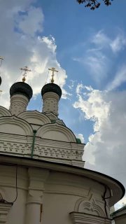 Купола храма с крестами на фоне облачного неба, вид снизу, контрастные формы и свет, характерная церковная архитектура.