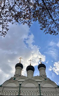 Вертикальный кадр куполов и облаков, три креста над барабанами, нежный весенний свет и архитектурный фрагмент московского храма.