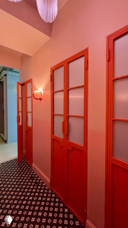 Коридор и двери в интерьере «Лолиты»: розовые и коралловые оттенки, декоративные панели и узорчатое ковровое покрытие ресторана.