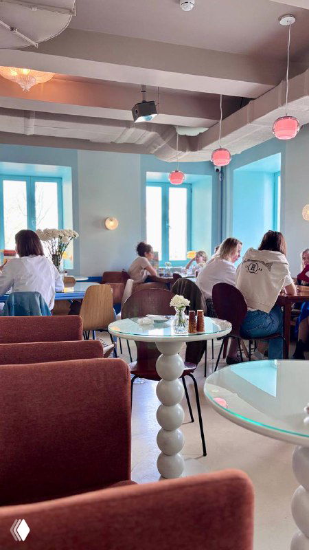 Общий вид зала «Лолиты»: посетители за столиками, большие окна с голубыми рамами, мягкие диваны и светлая уютная обстановка.