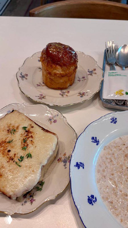 Тарелка с маленьким куличом в карамельной шапке, рядом крокмадам с крабом и овсяная каша — крупный план подачи завтрака в кафе.