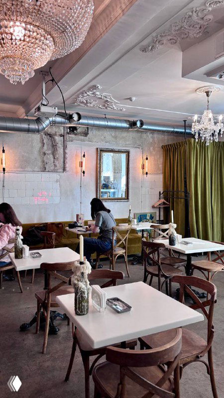 Интерьер зала кафе с люстрами, столиками и шторами; стильное пространство, где иногда проходят киновечера и показы в оригинале.