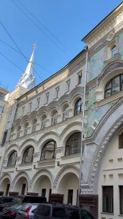 Широкий вид на изогнутый фасад и ряд арочных окон Саввинского подворья, показывающий протяжённость декоративной стены и фронтона.