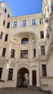 Вид уютного внутреннего двора с балконами, арочными проёмами и отделкой фасадов, типичный пример московской дворовой архитектуры.