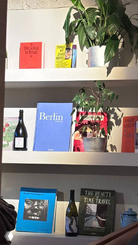 Полка с книгами, растениями и декоративными предметами внутри ресторана from Berlin, уютный уголок интерьера заведения.