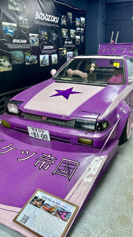 Сиреневая машина из субкультуры босодзоку с фиолетовой окраской и звёздой на капоте, экспонат музея с табличкой и информацией у борта.