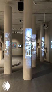 Зал с колоннами и множественными вертикальными проекциями движущихся фигур танцоров — современная инсталляция части экспозиции.