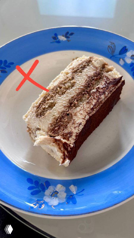 Порция тирамису на синей тарелке в домашней подаче; фотография помечена крестом, как непризнанный по вкусу вариант.