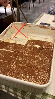 Большой противень тирамису с вырезанными кусками на столе кафе; снимок отмечен красным крестом, показывает массовый неудачный пример.
