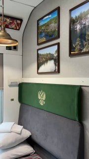 Крупный план интерьера купе: зелёный подголовник, декоративные рамки с пейзажами, витражи и медная подвесная лампа.