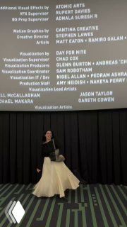 Человек стоит на фоне большого экрана с финальными титрами фильма; кадр из зала или видео про поход в кино, тёмная фигура на переднем плане.