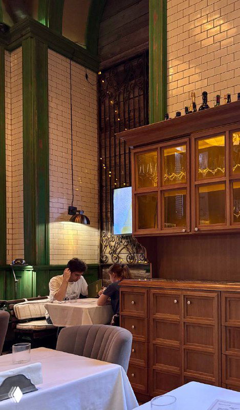 Посетители сидят за столом в уютном уголке ресторана Christian; на заднем фоне деревянные элементы и полки — часть обстановки на Кутузовском проспекте