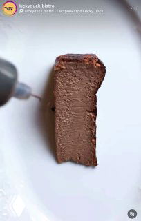 Продольный ломтик шоколадного чизкейка на тарелке, в кадре видна подача бальзамического соуса — момент сервировки в Lucky Duck.