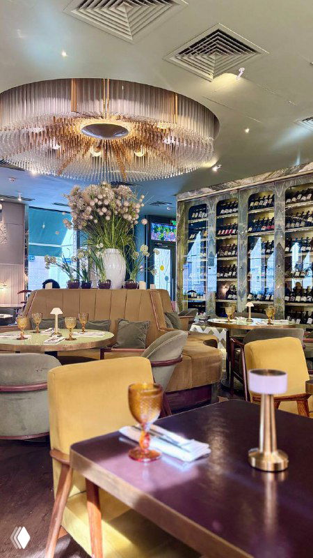 Интерьер нео‑бистро Geraldine: уютная обеденная зона с мягкими диванами, большой люстрой и винными полками — дневная атмосфера ресторана в Москве.