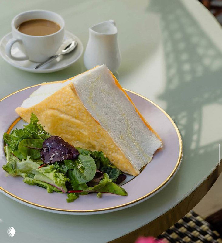 Завтрак с яйцами и сэндвичем на пастельно-фиолетовой тарелке, рядом чашка кофе и молочник — нежная подача утреннего блюда на веранде.