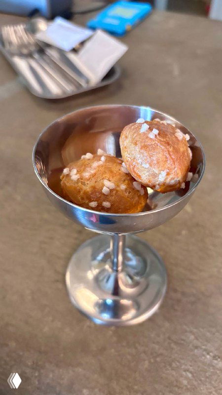 Маленькая серебряная рюмка с заварными булочками, посыпанными крупной солью, комплимент от кухни бистро Метеорит.