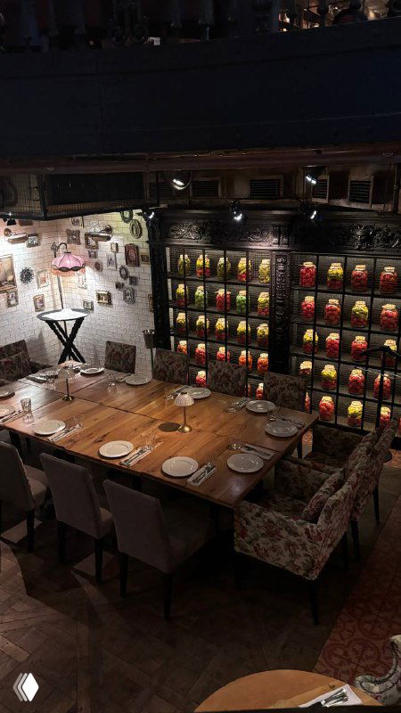 Большой сервированный стол для компании, декоративная настенная полка с предметами декора и уютная постановка для группового ужина.