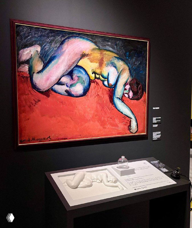 Большая картина с лежащей фигурой в насыщенных контрастных цветах, рядом визитка экспоната и музейная витрина с информацией.