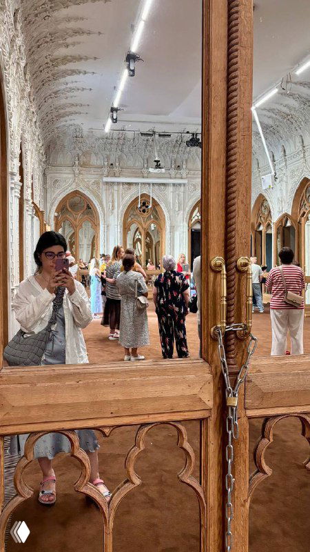 Посетители отражаются в зеркале дворцового интерьера: люди в зале осматривают орнаментальную лепнину и декоративные двери усадьбы