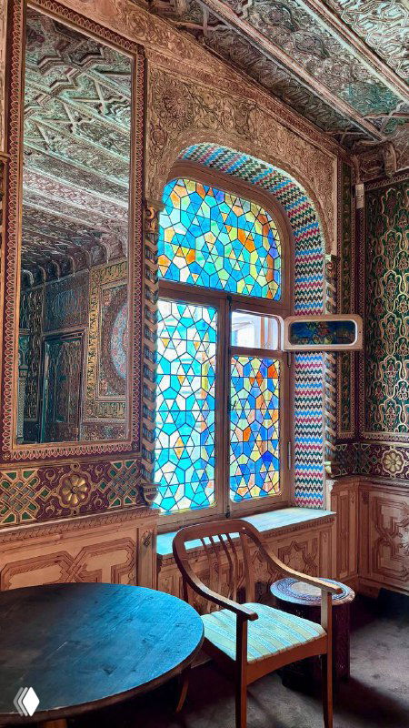 Витражное окно и фигурная расписная отделка арабского зала усадьбы: стол и деревянное кресло на фоне цветного стекла и мозаики