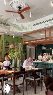 Интерьер бистро Le Pigeon в Москве: светлый зал, столы, цветочные композиции и барная зона, кадр сделан с высоты сидящего посетителя.