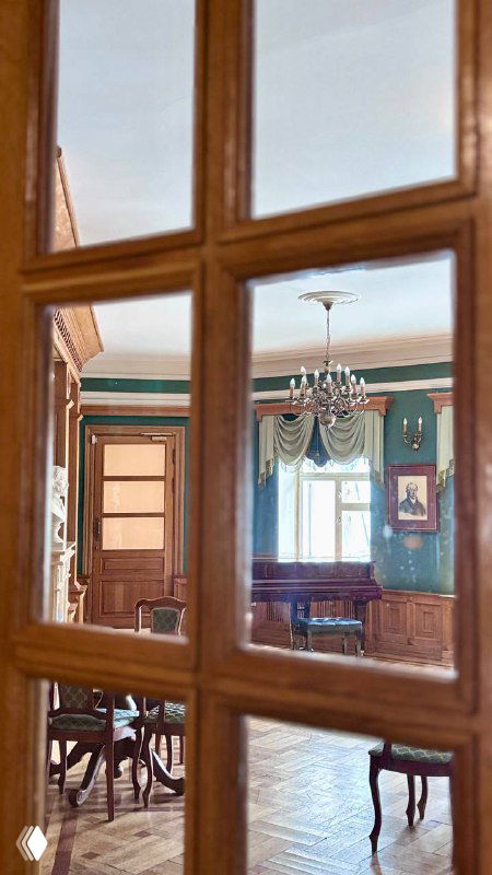 Интерьер с видом через стеклянные двери на соседний зал: деревянная мебель, люстра и мягкие тона помещения, классический ретро‑интерьер.