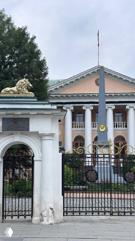 Вход в посольство Армении: ворота, колонны и два золотых льва у входа перед фасадом официального здания, классическая архитектура посольства.