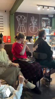 Участники мастер‑класса по жестовому языку сидят у стойки в кофейне, слушают и выполняют задания, видна атмосфера мероприятия.