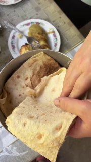 Свежий тонкий лаваш, который разворачивают для подачи шашлыка, видно текстуру хлеба и руки, формирующие подачу