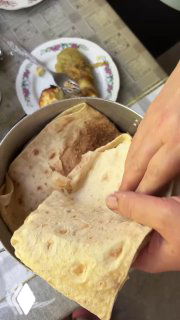 Лаваш, которым оборачивают свежеприготовленный шашлык, крупным планом: тонкий хлеб готовят, чтобы сохранить сочность мяса после снятия с огня.