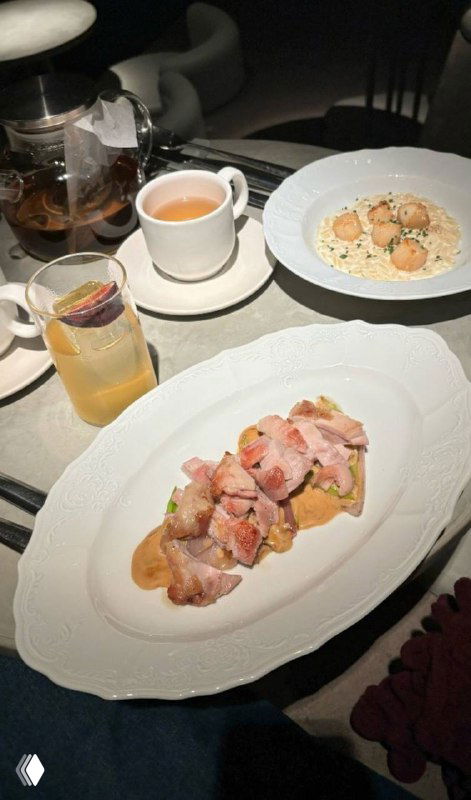 Крупный план тарелки с нарезанным мясным блюдом (бедро куриное) и имбирным соусом, рядом чашка и приборы в ресторане Soma