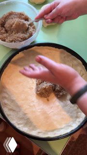 Выкладывание ореховой пасты ложкой на тонкий слой теста, равномерное распределение начинки в форме перед закрытием.