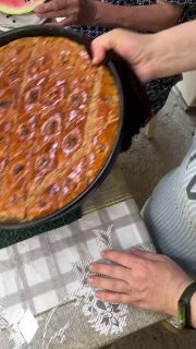 Группа людей держит форму с пахлавой, видно передачу горячей выпечки и совместную домашнюю атмосферу.