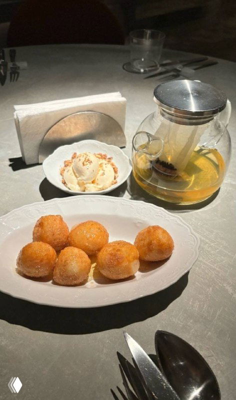 Медовые пышки с мороженым и грецким орехом на белой тарелке, рядом прозрачный чайник и сервировка в ресторане Soma