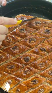 Нанесение сиропа или глазури на горячую пахлаву маленькой ложкой, смазка каждого ромбика для баланса сладости.